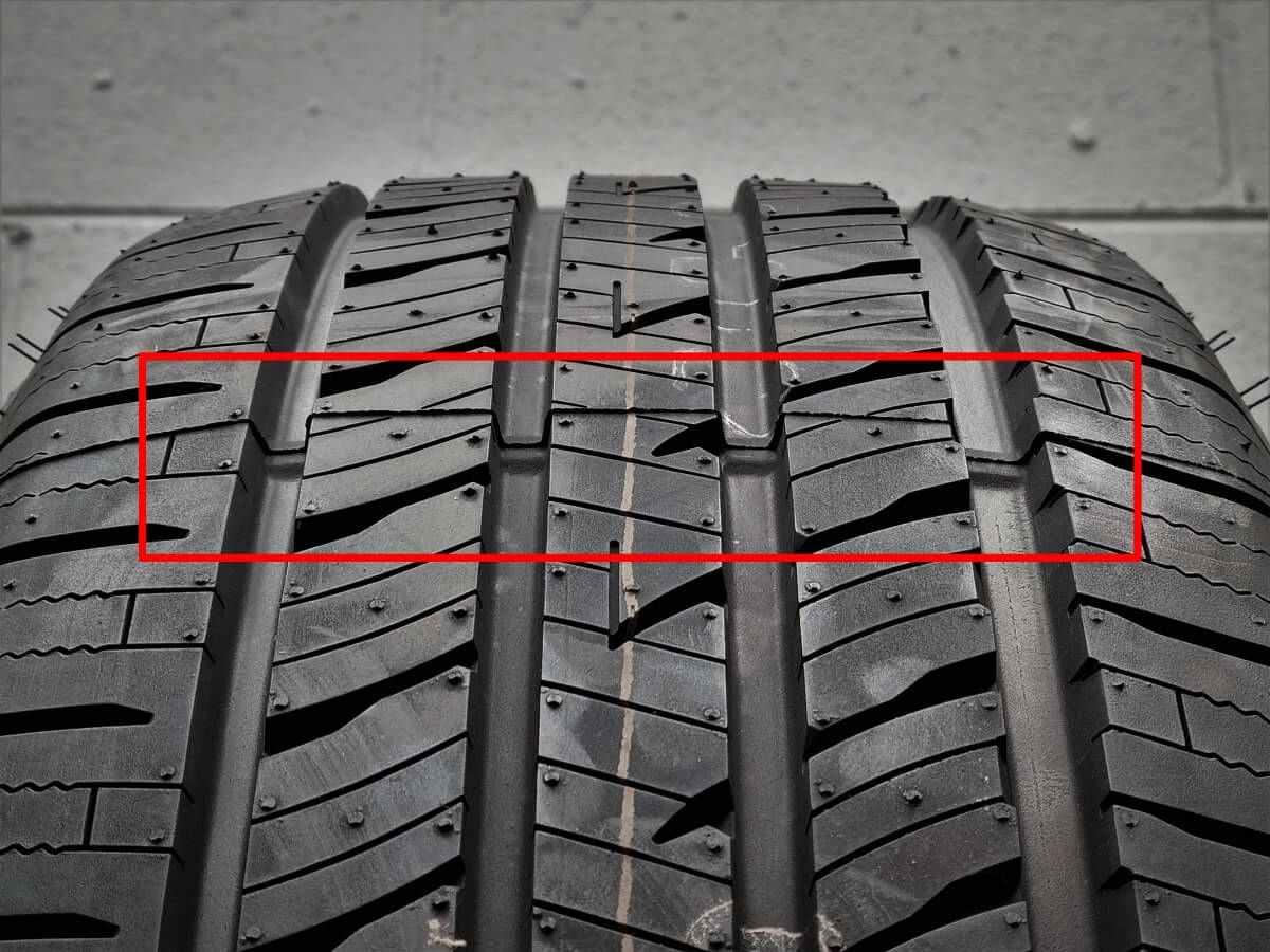 Closeup of a tread wear indicator bar inside a tire groove